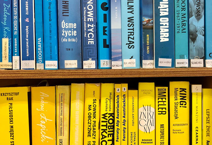 2 rzędy książek, górny rząd prezentuje książki z grzbietem w kolorze niebieskim, dolny z grzbietem w kolorze żółtym tak aby imitowały flagę Ukrainy.