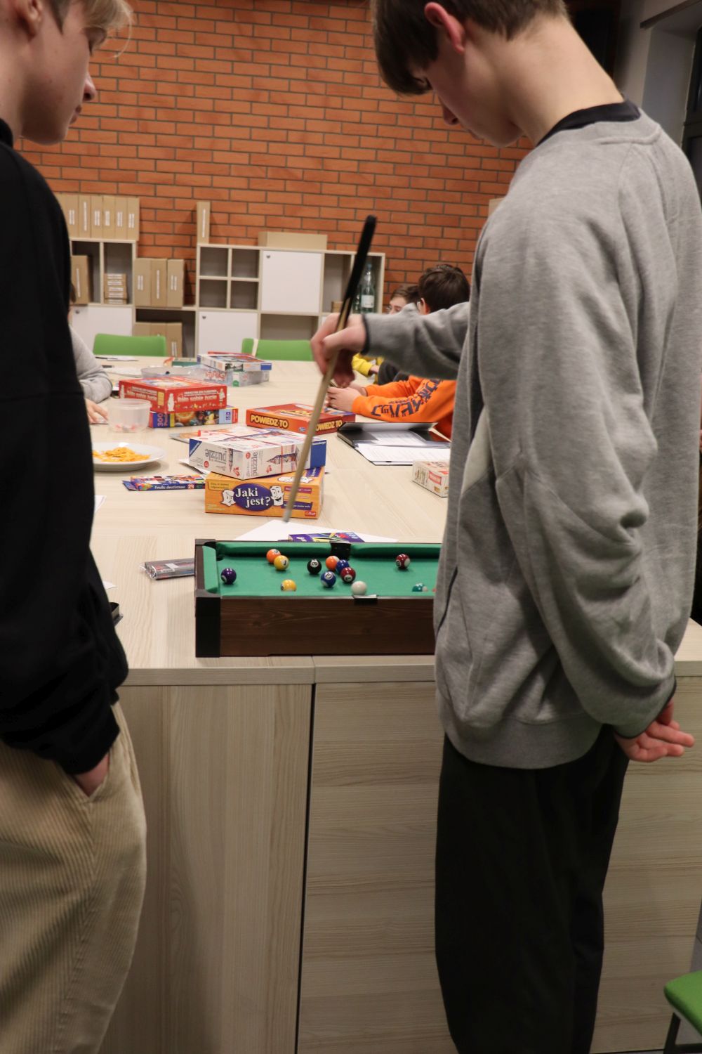 spotkanie klubu dla młodzieży, dwaj chłopcy stoja przy stole, na którym ustawiony jest mini-bilard